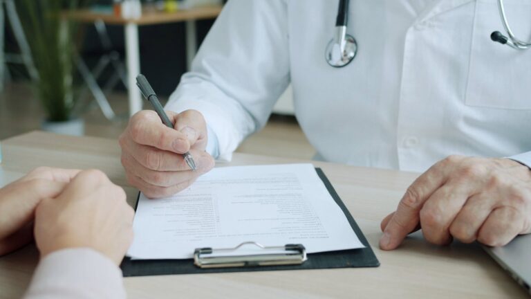 A clinician filling in a form on a clipboard
