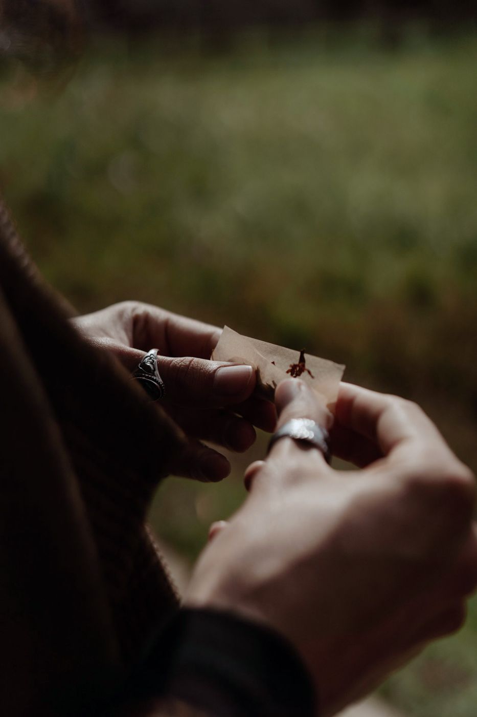 Hands rolling a cigarette from loose tobacco