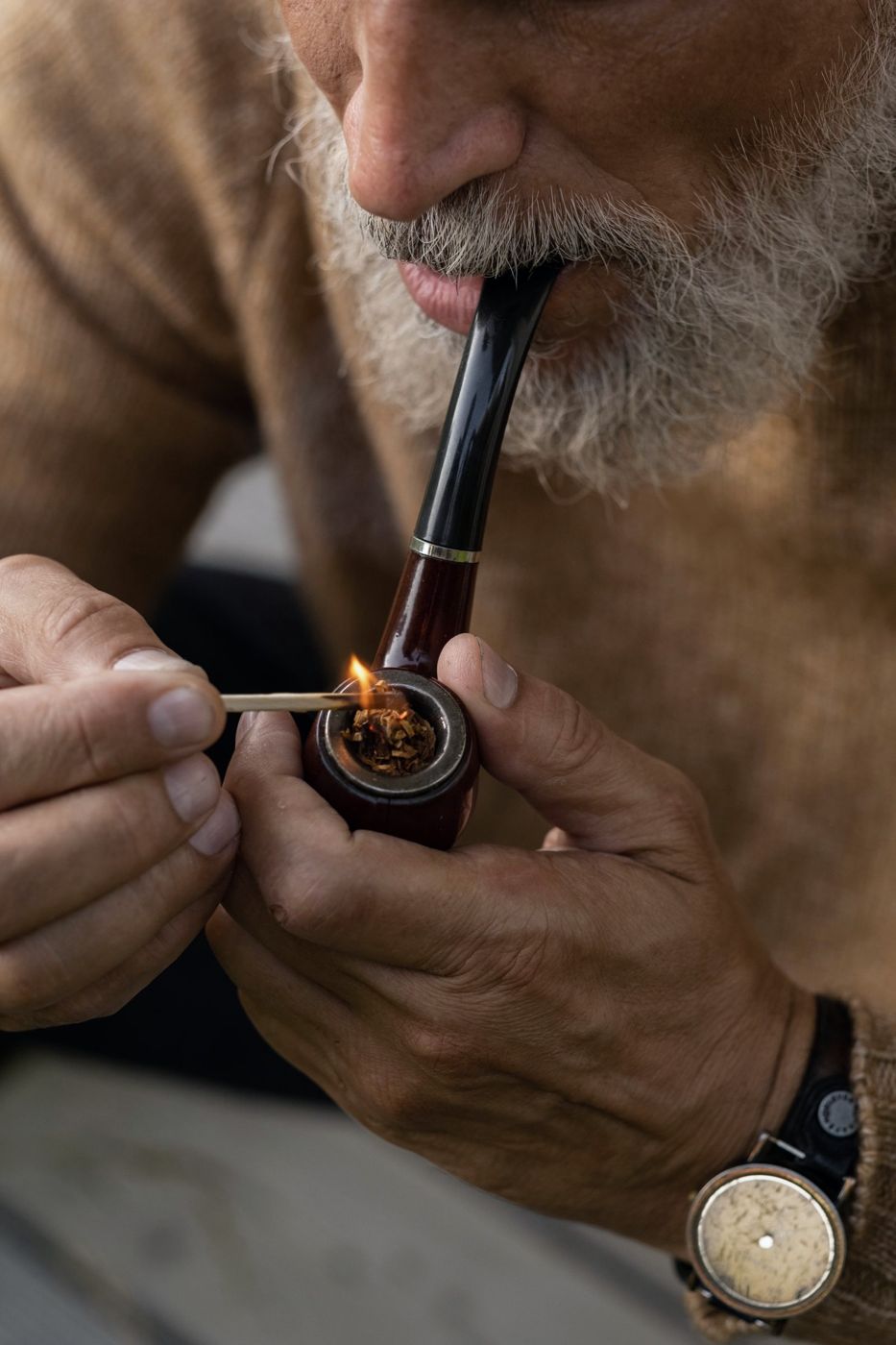 An older man lighting a tobacco pipe