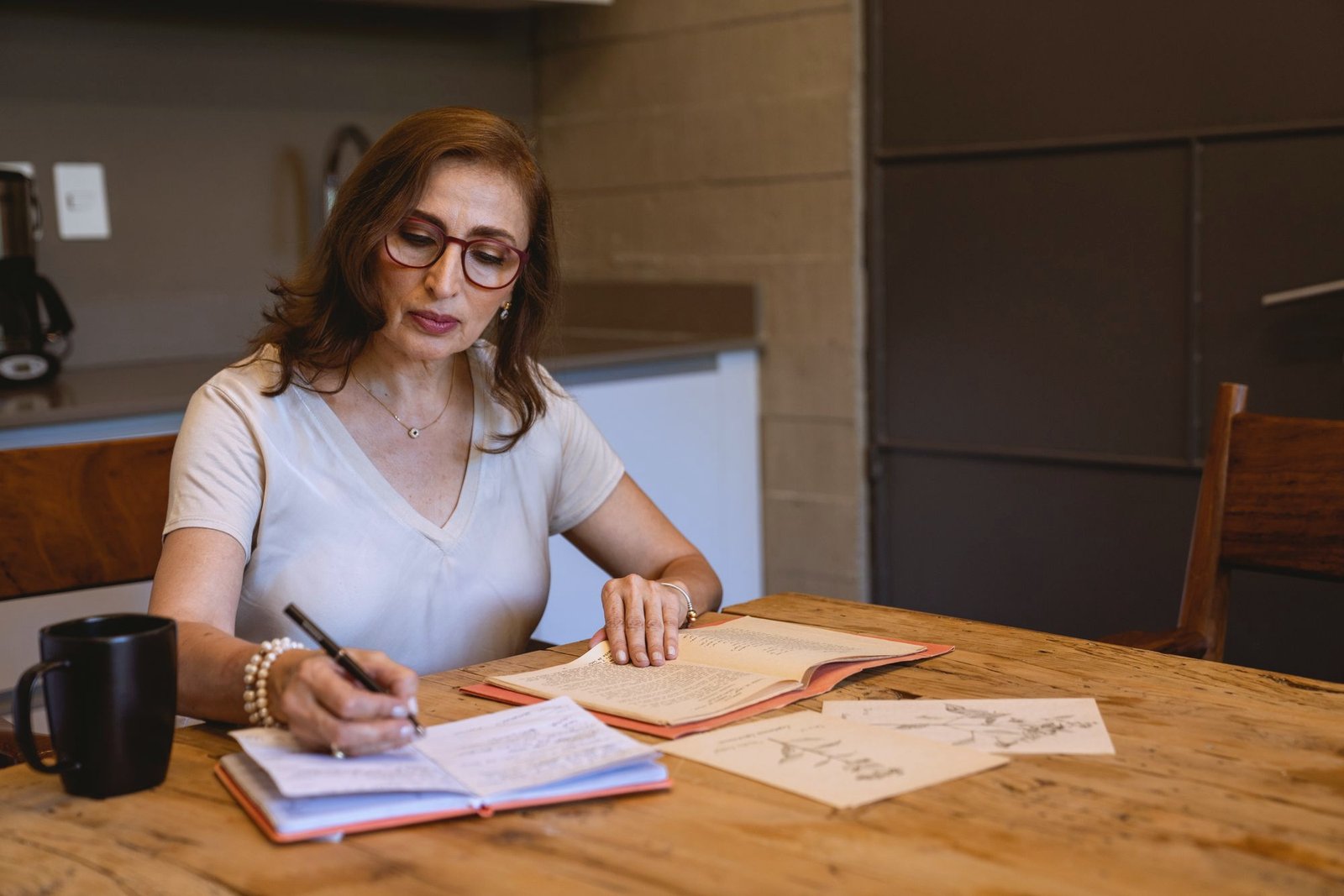 A woman writing notes at her kitchen table